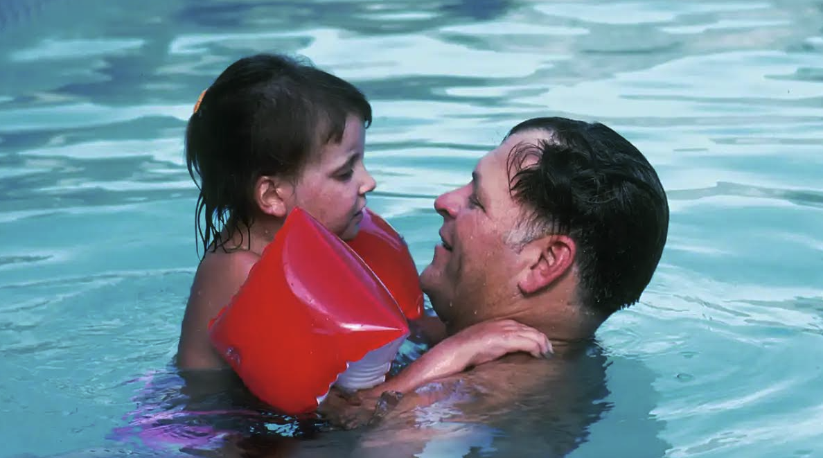 Girl in the pool with her father